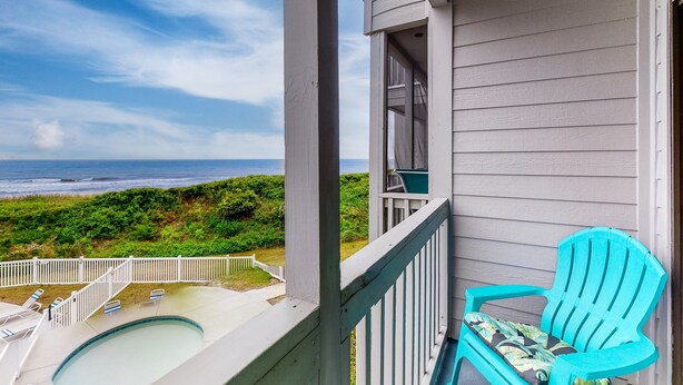 A balcony with a view of the ocean, a pool, and a turquoise chair. - 2nd-Floor Condo in Oceanfront Location w/WiFi, Screened-In Balcony, Shared Pool (Atlantic Beach)