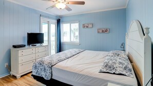 Ein Schlafzimmer mit einem Bett, einem Schminktisch, einem Fernseher und einem Deckenventilator.