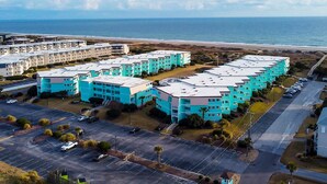 A multi-story residential building with a parking lot and a view of the ocean. - Condo with on-site beach access, pools, grill/picnic areas, & private balcony (Atlantic Beach)