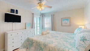 A bedroom with a bed, a ceiling fan, a dresser, a TV, and a window with curtains. - Condo with on-site beach access, pools, grill/picnic areas, & private balcony (Atlantic Beach)