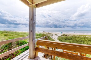 A wooden deck with a view of a beach and dunes.