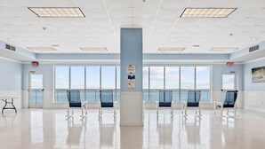 A spacious room with large windows, a central pillar, and several chairs arranged for seating.