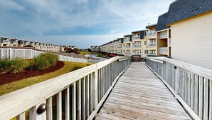 Een houten looppad dat leidt naar een rij moderne appartementencomplexen met balkons.