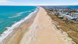 Luchtbeeld van een strand met een rij huizen langs de kustlijn.