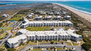 Een woongebied aan de kust met appartementencomplexen, een strand en een parkeerplaats.