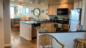 A modern kitchen with a central island, wooden cabinets, a microwave, and a refrigerator.