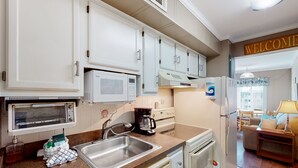 A kitchen with white cabinets, a microwave, a coffee maker, and a sink. - 3rd-Floor Condo Overlooking Courtyard w/Beach Views, WiFi, Shared Pools/Hot Tub (Atlantic Beach)