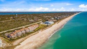 Ett hotell vid kusten med flera byggnader längs strandpromenaden, en sandstrand och utsikt över havet.