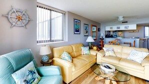 A living room with two sofas, a coffee table, and a ship's wheel decoration.