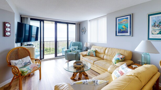 A living room with a sofa, armchairs, a television, and a large window.