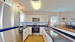 Una cocina moderna con electrodomésticos de acero inoxidable, armarios blancos y piso de madera.