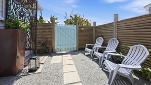 A patio with Adirondack chairs, a decorative metal gate, and a wooden fence. - Mermaid Cove:  Minutes to beach (Atlantic Beach)