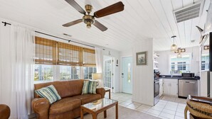 A living room with a brown leather sofa, a glass coffee table, and a ceiling fan. - Mermaid Cove:  Minutes to beach (Atlantic Beach)