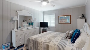 A bedroom with a bed, dresser, television, and a ceiling fan. - Beautifully Remodeled, Oceanfront, 3rd-Floor Condo with Balcony & Shared Pools (Atlantic Beach)