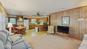 A living room with a sofa, a television, and a dining area with a table and chairs. - Perfect 3BR Getaway with Central A/C, Full Kitchen and Relaxing Balcony (Emerald Isle)