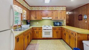 A kitchen with wooden cabinets, a white refrigerator, a stove, and a microwave. - Perfect 3BR Getaway with Central A/C, Full Kitchen and Relaxing Balcony (Emerald Isle)