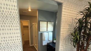 A hallway with patterned wallpaper, a potted plant, and a glimpse of a bathroom with a towel rack. - Bright 4-bedroom house with AC in Lathrop (Lathrop)