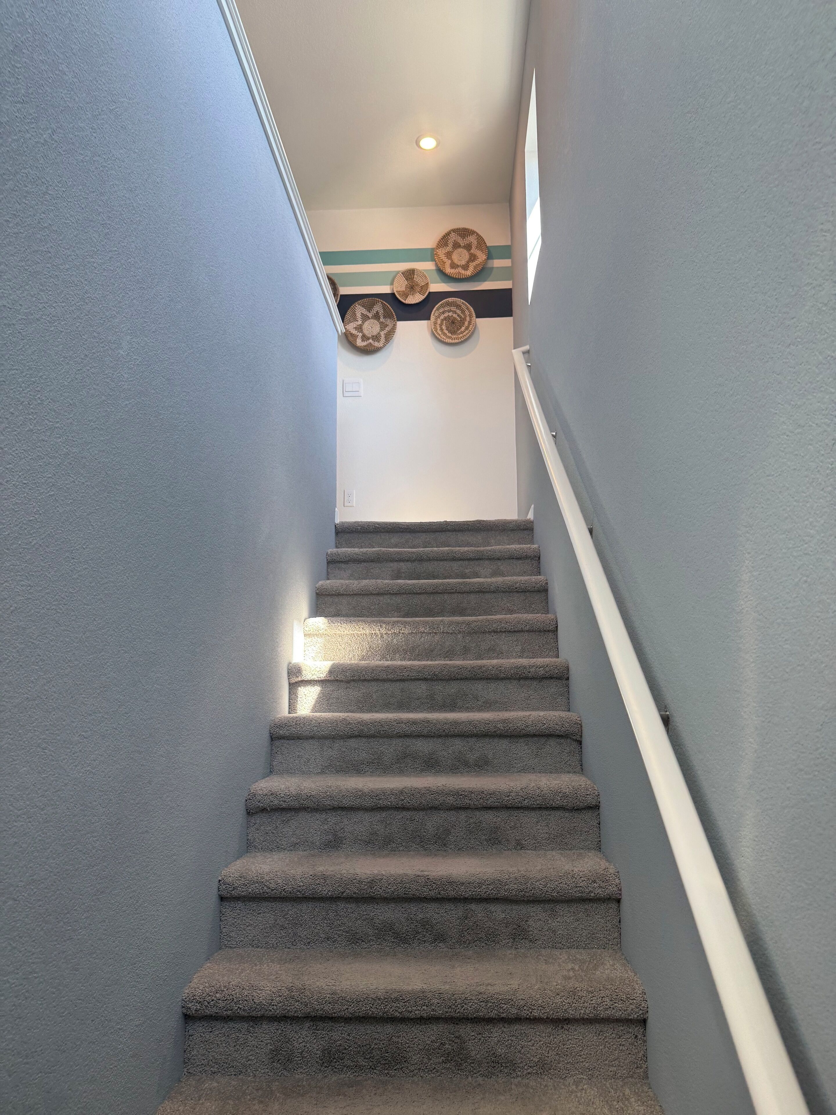 Een bekleed trap met een leuning, leidend naar een plateau met decoratieve wandversieringen.