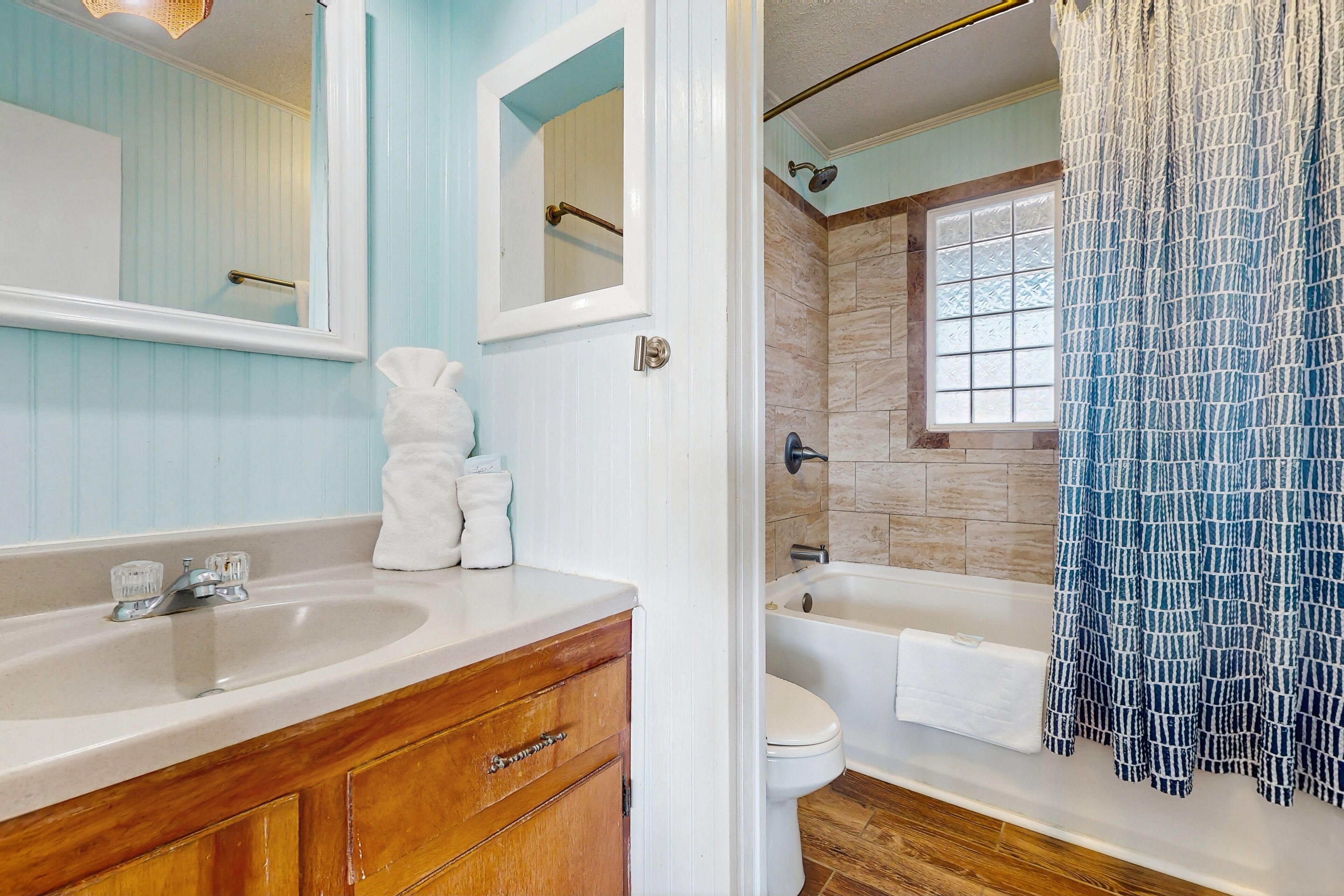 A bathroom with a sink, mirror, and a shower area.