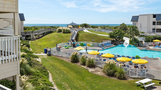 Een resort met een zwembad, terras en een glijbaan.