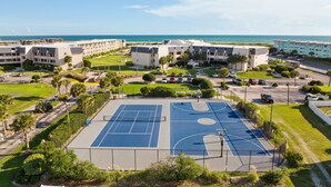 Een luchtendienst van een hotelcomplex met meerdere gebouwen, een basketbalveld en een parkeerplaats.