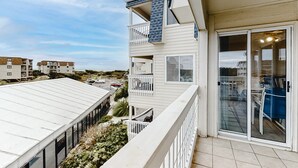 A multi-story residential building with balconies, a sliding glass door entrance, and a view of the surrounding neighborhood. - Oceanfront, 2nd-Floor Condo with Balcony, WiFi & Shared Hot Tub/Pools/Putt-Putt (Atlantic Beach)