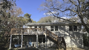 A two-story house with a wooden deck and a staircase leading to the upper floor.