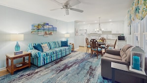A living room with a striped sofa, a coffee table, and a dining area with chairs and a table.