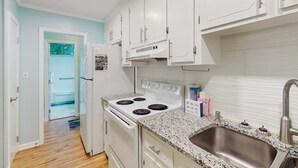 A kitchen with white cabinets, a stainless steel sink, and a white stove.