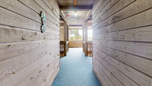 A wooden hallway with a blue carpet, wooden walls, and a ceiling with exposed beams. - First-Floor Condo with Balcony, WiFi & Shared Pools, Hot Tub, Tennis, Putt-Putt (Atlantic Beach)