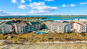 A beachfront hotel with multiple buildings, a swimming pool, and a view of the ocean and distant land. - Oceanfront condo with shared pool, beach access and ocean views (Atlantic Beach)