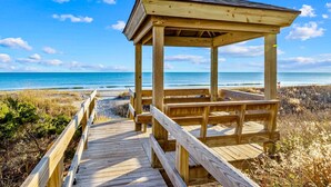 A wooden beach gazebo with a wooden deck leading to it, overlooking a beach and ocean. - Oceanfront condo with shared pool, beach access and ocean views (Atlantic Beach)