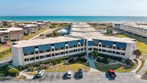 A multi-story hotel with a parking lot, adjacent to a beach. - First-Floor Condo with Courtyard View, WiFi & Shared Pools/Hot Tub/Putt-Putt (Atlantic Beach)