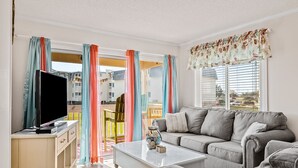 A living room with a sofa, TV, and a coffee table. - First-Floor Condo with Courtyard View, WiFi & Shared Pools/Hot Tub/Putt-Putt (Atlantic Beach)
