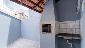 Un petit espace extérieur clos, doté d’un sol carrelé, d’un évier intégré et d’une grille de ventilation.