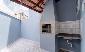 A small, enclosed outdoor space with a tiled floor, a built-in sink, and a ventilation grate. - Casa c/ Churrasqueira em Ingleses RIS0006 (Florianópolis)