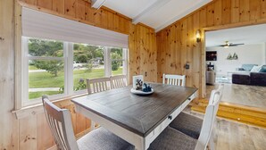 Ein Essbereich mit Holztisch und Stühlen, einem Fenster mit Blick auf Grünflächen und einem Deckenventilator.