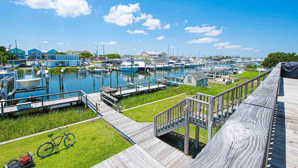 Un marina con barche ormeggiate, passerelle in legno e una zona verde con una bicicletta.