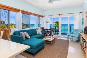 A spacious living room with a teal sofa, a coffee table, and a view of the ocean through large windows. - Teal Horizon OceanfrontCaribbean Escape (Tower Isle)