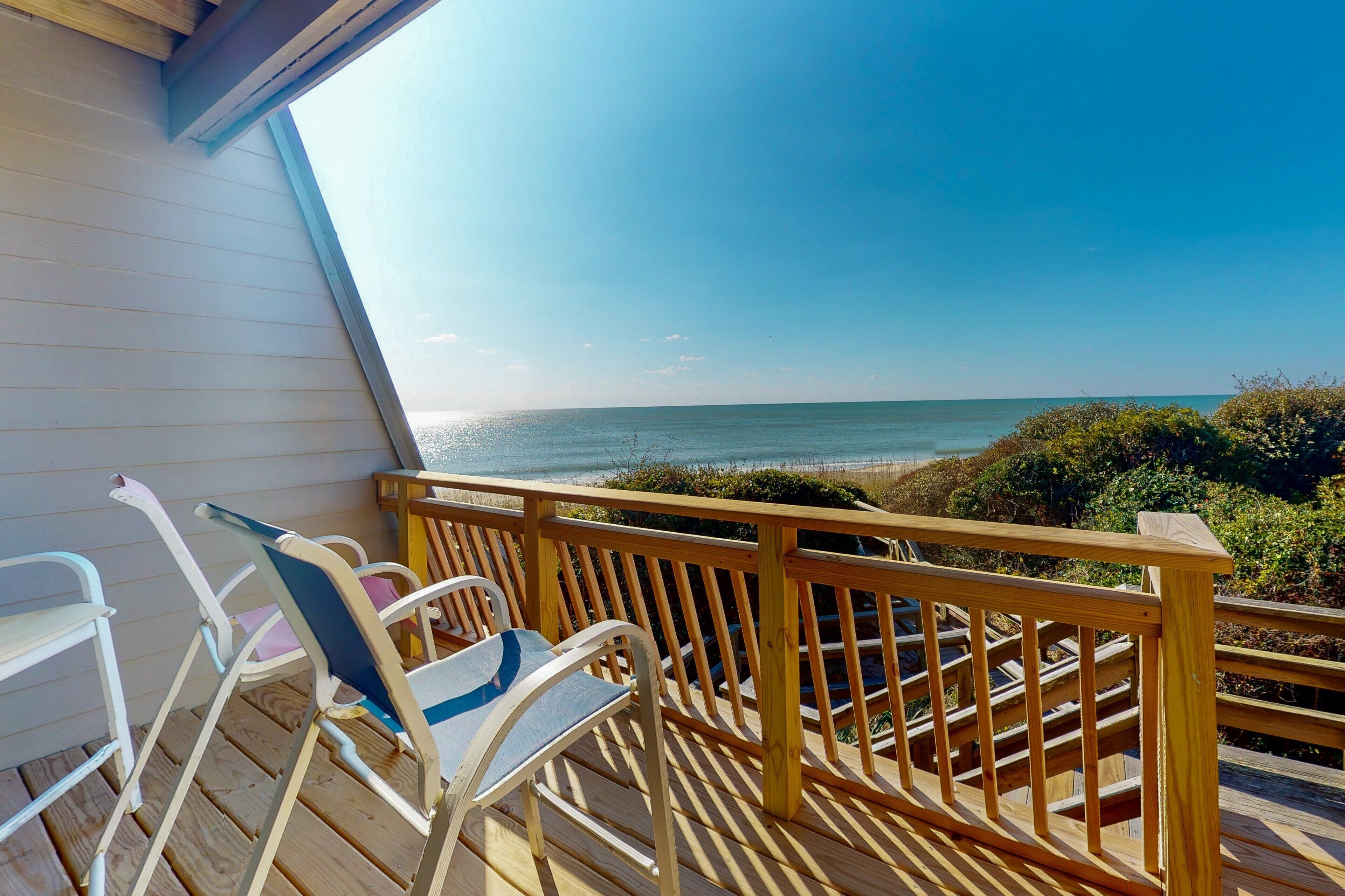 A wooden deck with a view of the ocean and beach.