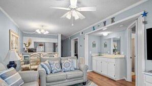 A living room with a grey sofa, patterned cushions, a striped rug, and a ceiling fan. - 2nd-floor condo with beach access, in/outdoor pools, hot tub, sports courts, AC (Atlantic Beach)