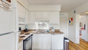 A modern kitchen with white cabinets, a granite countertop, stainless steel appliances, and a sign that reads "sweet & salty." - Remodeled condo with pool, WiFi, W/D & AC - next to state park (Atlantic Beach)