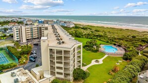 A hotel with multiple floors, a rooftop pool, and a beach view.