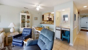 A compact living space with a dining area, kitchenette, and seating area. - Oceanfront, 2nd-Floor Condo with Great Ocean View, Balcony, WiFi & Shared Pool (Pine Knoll Shores)
