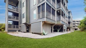 A multi-story residential building with balconies, a covered outdoor area, and a well-maintained lawn. - Condo by the ocean with a pool, tennis, WiFi, central AC - steps from the beach (Atlantic Beach)
