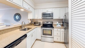 Een moderne keuken met witte kasten, roestvrijstalen apparatuur, een vaatwasser en een magnetron.