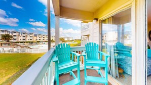 Een balkon met turquoise stoelen en uitzicht op een woonwijk.
