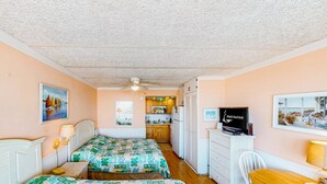 A bedroom with two beds, a desk, a chair, a television, and a kitchenette in the background. - Shorely Suite #204: Waterfront suite, pool, beach access (Atlantic Beach)
