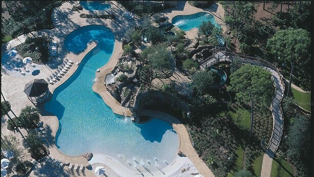 An aerial view of a resort with multiple swimming pools, sun loungers, and a well-maintained landscape. - Pristine 1-bedroom condo w/1.5 Bath in World Renowned Innisbrook Golf Community (Palm Harbor)