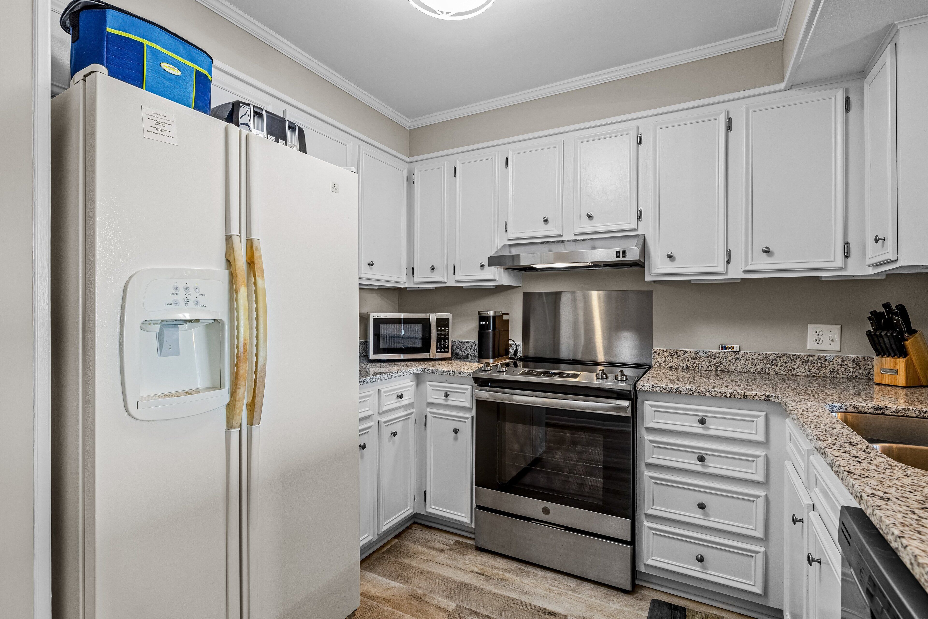 A kitchen with white cabinets, a stainless steel oven, a microwave, and a refrigerator.